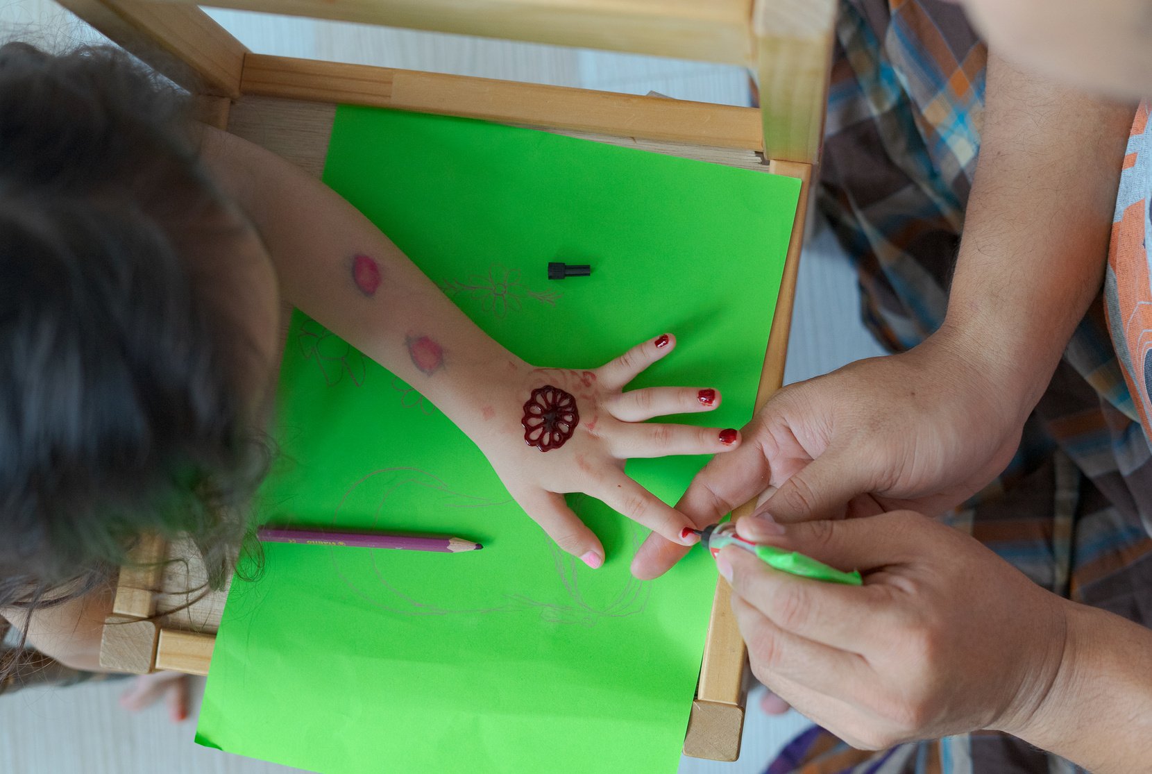 Parent Putting Henna Tattoo on a Kid's Hand 